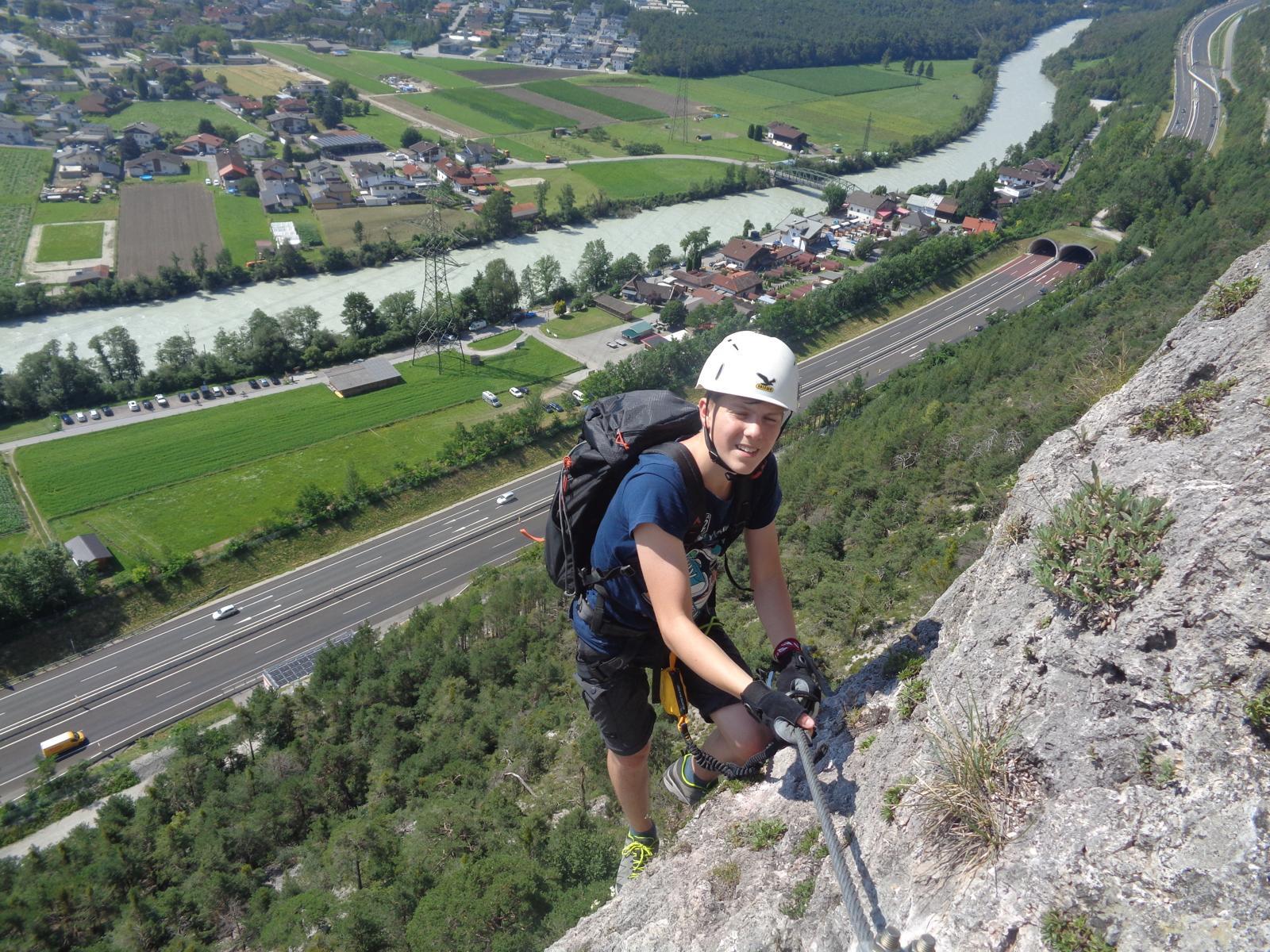 Seitliches Profil einer Frau mit rostrotem Rollkragenpullover und weißer Tasche. Sie blickt mit geschlossenen Augen auf.